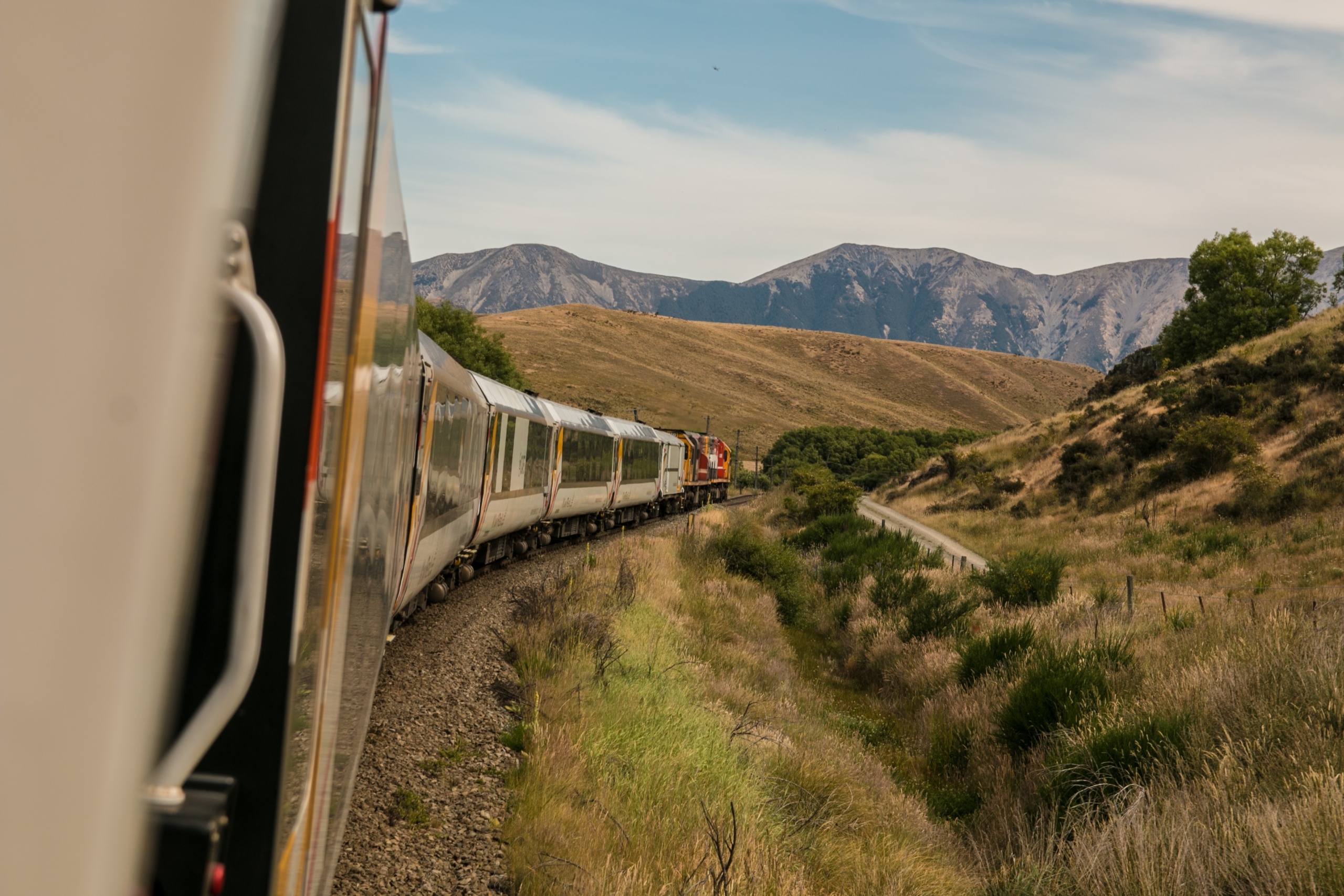 A passenger train travelling through wild, mountainous landscape.
